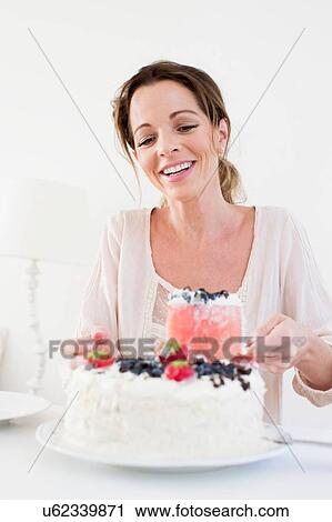 Mature woman serving fruit covered cake looking down smiling View Large Photo Image Stock Image - Mature woman serving fruit covered cake looking down smiling. Fotosearch