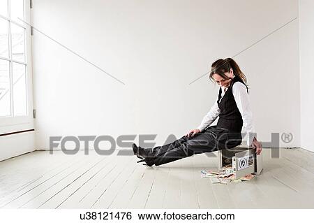 Mature woman sitting on safe in empty room, safe door open with money spilling out View Large Photo Image Stock Photograph - Mature woman sitting on safe in empty room, safe door open with money spilling out. Fotosearch