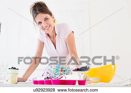 Mature woman wearing apron preparing food looking at camera smiling View Large Photo Image Stock Photo - Mature woman wearing apron preparing food looking at camera smiling. Fotosearch
