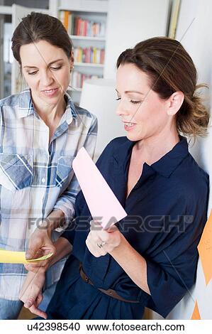 Stock Image - Mature women holding paperwork looking down. Fotosearch
