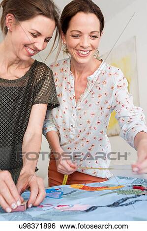 Mature women measuring colourful fabric, looking down smiling View Large Photo Image Stock Photograph - Mature women measuring colourful fabric, looking down smiling. Fotosearch