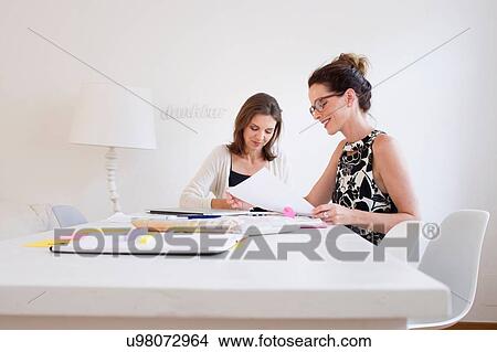 Mature women sitting at table looking at paperwork View Large Photo Image Picture - Mature women sitting at table looking at paperwork. Fotosearch