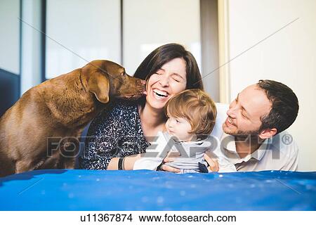 Mid adult couple laughing with toddler daughter and pet dog View Large Photo Image Picture - Mid adult couple laughing with toddler daughter and pet dog. Fotosearch