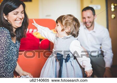 Mid adult couple playing with toddler daughter in living room View Large Photo Image Stock Photography - Mid adult couple playing with toddler daughter in living room. Fotosearch