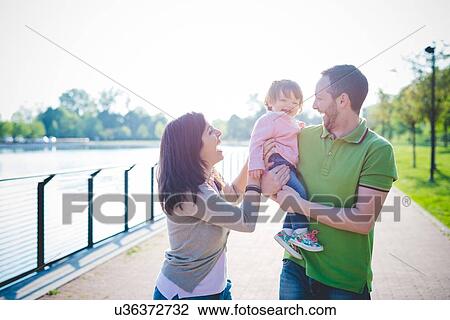 Stock Image - Mid adult couple with toddler daughter in park. Fotosearch