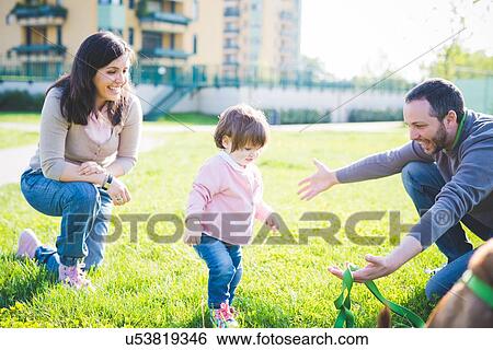 Mid adult couple with toddling toddler daughter in park View Large Photo Image Stock Photograph - Mid adult couple with toddling toddler daughter in park. Fotosearch