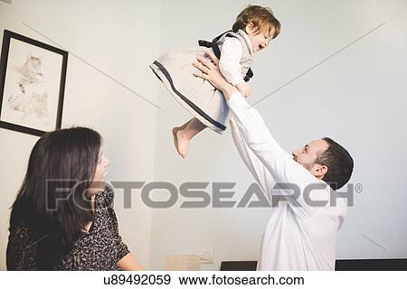 Mid adult man lifting up toddler daughter in living room View Large Photo Image Stock Photo - Mid adult man lifting up toddler daughter in living room. Fotosearch