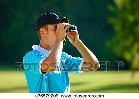 Mid adult man wearing baseball cap looking through binoculars View Large Photo Image Stock Photo - Mid adult man wearing baseball cap looking through binoculars. Fotosearch