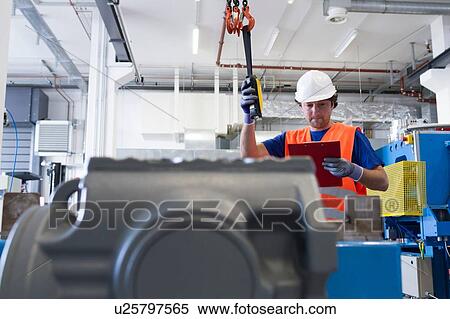 Mid adult man wearing hard hat operating machine, looking down at clipboard View Large Photo Image Stock Photography - Mid adult man wearing hard hat operating machine, looking down at clipboard. Fotosearch