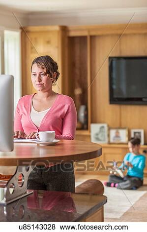 Mid adult mother working on computer whilst son playing View Large Photo Image Stock Photo - Mid adult mother working on computer whilst son playing. Fotosearch