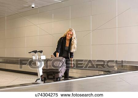 Mid adult woman collecting luggage from baggage claim area in airport and loading trolley View Large Photo Image Stock Photography - Mid adult woman collecting luggage from baggage claim area in airport and loading trolley. Fotosearch