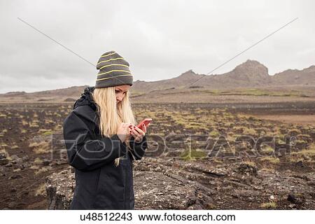 Mid adult woman on volcanic landscape wearing knitted hat using smartphone, Helgafell, Iceland View Large Photo Image Stock Image - Mid adult woman on volcanic landscape wearing knitted hat using smartphone, Helgafell, Iceland. Fotosearch