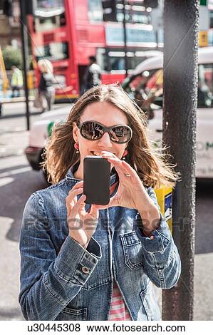 Mid adult woman wearing sunglasses taking smartphone selfie on street, London, England, UK View Large Photo Image Stock Photo - Mid adult woman wearing sunglasses taking smartphone selfie on street, London, England, UK. Fotosearch