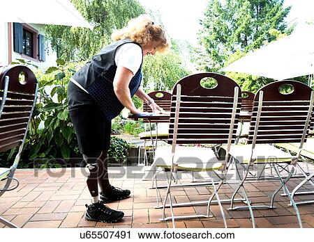 Stock Image - Mid adult woman with prosthetic leg, on patio. Fotosearch