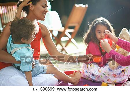 Stock Photo - Mother and children playing picnics at garden birthday party. Fotosearch