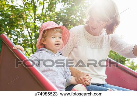 Mother and female toddler playing on park slide View Large Photo Image Stock Image - Mother and female toddler playing on park slide. Fotosearch