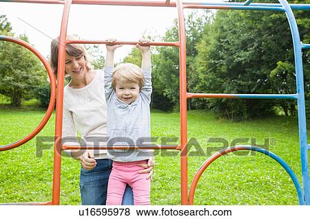 Mother and female toddler playing on park climbing frame View Large Photo Image Stock Photo - Mother and female toddler playing on park climbing frame. Fotosearch
