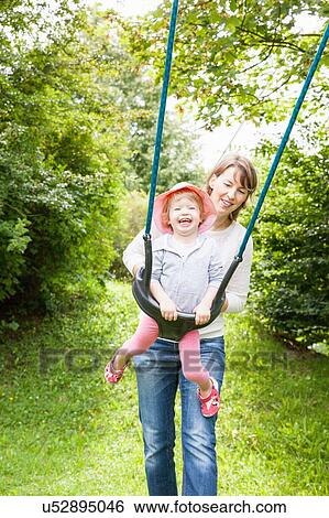 Mother and female toddler playing on park swing View Large Photo Image Stock Photograph - Mother and female toddler playing on park swing. Fotosearch