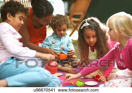 Stock Image - Mother and four children playing picnics at garden birthday party. Fotosearch