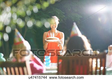 Mother carrying birthday cake to table at garden birthday party View Large Photo Image Picture - Mother carrying birthday cake to table at garden birthday party. Fotosearch