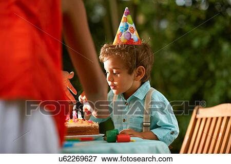 Mother with son blowing candles on birthday cake at garden birthday party View Large Photo Image Stock Photo - Mother with son blowing candles on birthday cake at garden birthday party. Fotosearch