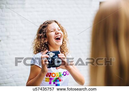 Over shoulder view of two happy tween girls photographing with instant camera View Large Photo Image Stock Photo - Over shoulder view of two happy tween girls photographing with instant camera. Fotosearch