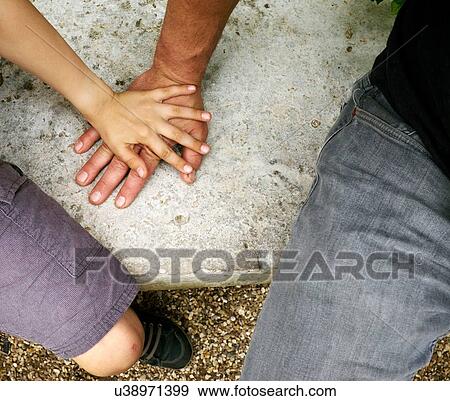 Stock Photo - Overhead view of boys hand on top of fathers hand. Fotosearch