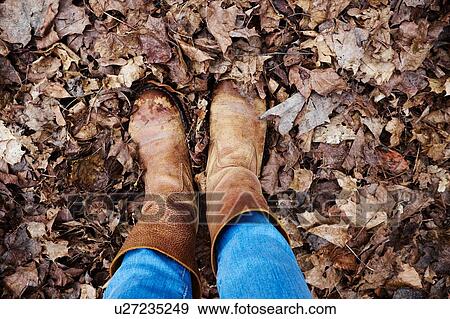 Stock Photo - Overhead view of woman wearing boots standing in autumn leaves. Fotosearch