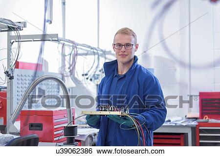 Stock Photograph - Portrait of apprentice electronics worker in electronics factory,. Fotosearch
