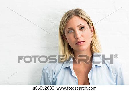 Stock Photograph - Portrait of beautiful young woman in front of white wall. Fotosearch