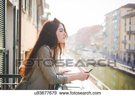 Portrait of beautiful young woman gazing from waterfront balcony View Large Photo Image Stock Photo - Portrait of beautiful young woman gazing from waterfront balcony. Fotosearch