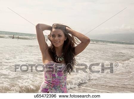 Portrait of beautiful young woman with hand in hair at beach View Large Photo Image Stock Photograph - Portrait of beautiful young woman with hand in hair at beach. Fotosearch