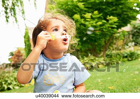Portrait of cute girl blowing bubbles in garden View Large Photo Image Picture - Portrait of cute girl blowing bubbles in garden. Fotosearch