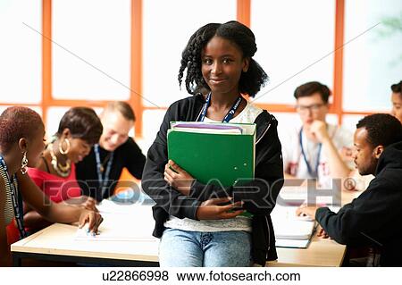 Stock Photo - Portrait of female student holding file in class. Fotosearch