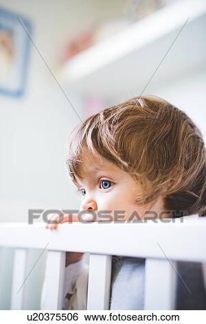 Portrait of female toddler gazing from crib View Large Photo Image Stock Photograph - Portrait of female toddler gazing from crib. Fotosearch
