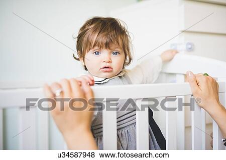Stock Photo - Portrait of female toddler staring from crib. Fotosearch