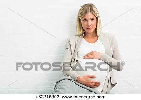 Stock Photo - Portrait of full term pregnancy young woman sitting holding stomach. Fotosearch