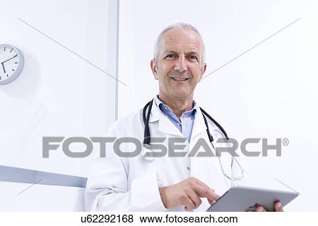 Stock Photo - Portrait of male doctor using digital tablet. Fotosearch