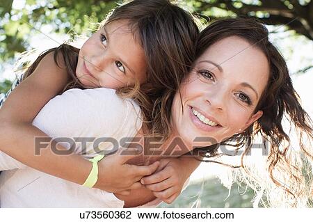 Portrait of mature woman giving daughter piggy back in park View Large Photo Image Stock Image - Portrait of mature woman giving daughter piggy back in park. Fotosearch
