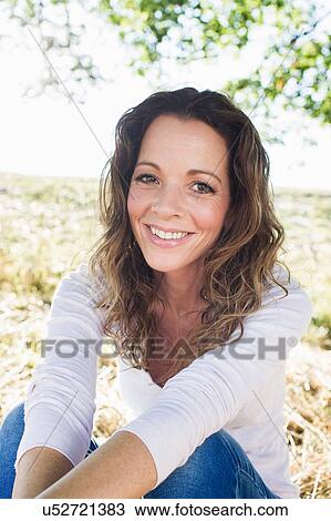 Stock Image - Portrait of mature woman sitting in park. Fotosearch