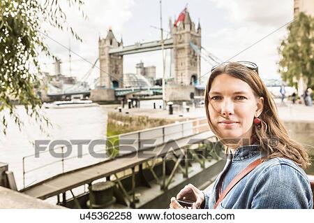 Stock Photo - Portrait of mid adult woman at Tower Bridge, London, England, UK. Fotosearch