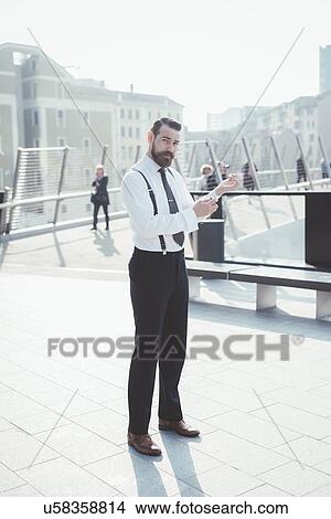 Picture - Portrait of stylish businessman fastening shirt cuffs on footbridge. Fotosearch