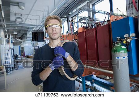 Stock Image - Portrait of technician holding component in factory. Fotosearch