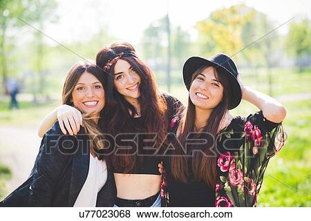 Stock Photo - Portrait of three stylish young female friends in park. Fotosearch
