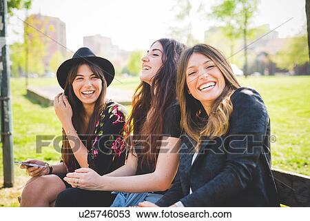 Portrait of three young female friends laughing in park View Large Photo Image Stock Image - Portrait of three young female friends laughing in park. Fotosearch