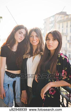 Stock Photo - Portrait of three young female friends on city balcony. Fotosearch