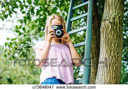 Portrait of tween girl taking instant photographs in garden View Large Photo Image Stock Photo - Portrait of tween girl taking instant photographs in garden. Fotosearch