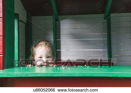 Portrait of young girl peering over ledge, smiling View Large Photo Image Stock Photograph - Portrait of young girl peering over ledge, smiling. Fotosearch