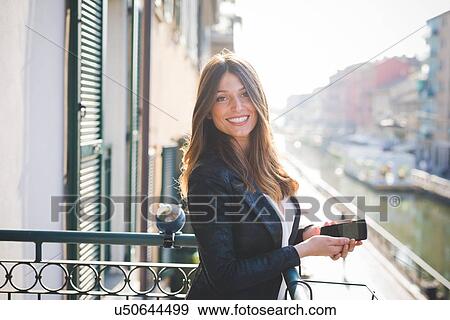 Portrait of young woman with smartphone on waterfront balcony View Large Photo Image Stock Photo - Portrait of young woman with smartphone on waterfront balcony. Fotosearch