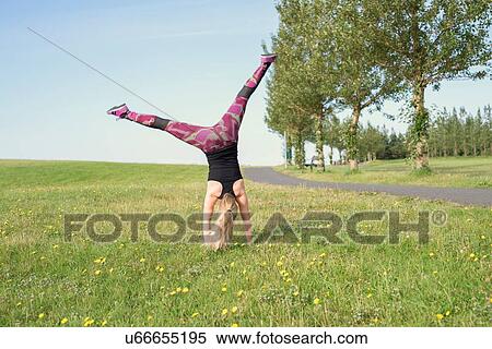 Stock Photography - Rear view of female runner cartwheeling in park. Fotosearch